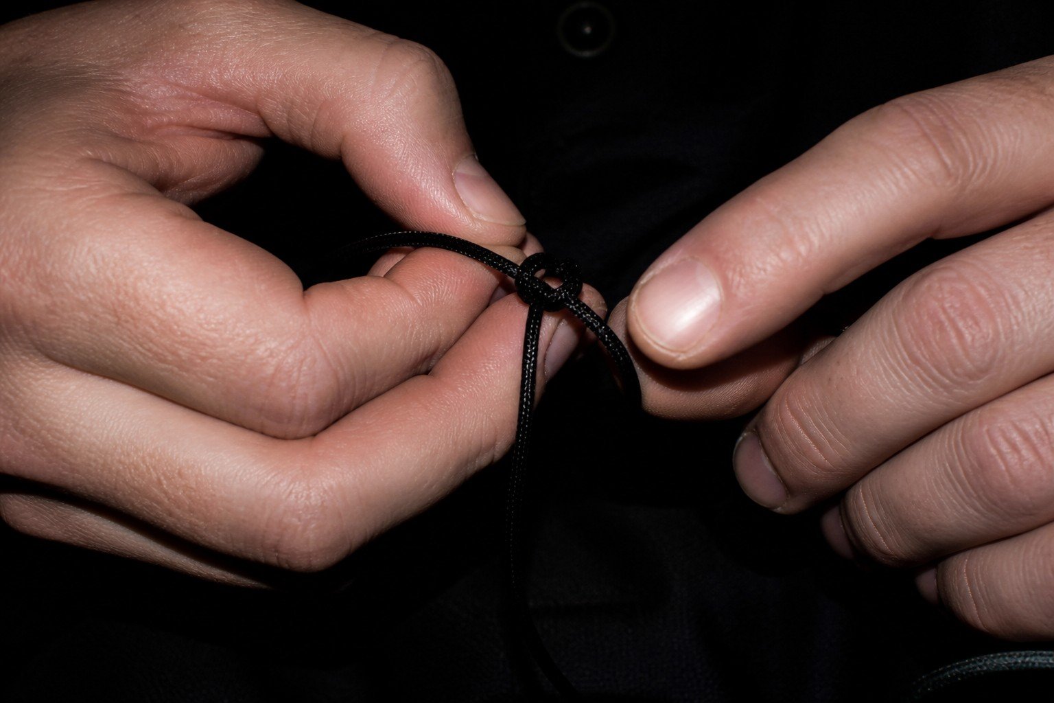 Manos anudando un cordón fino